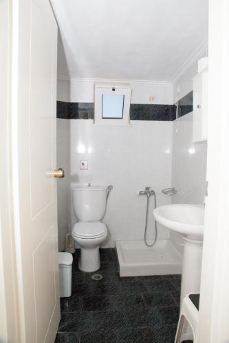 a white bathroom with a toilet and a sink at Meandros in Almirida
