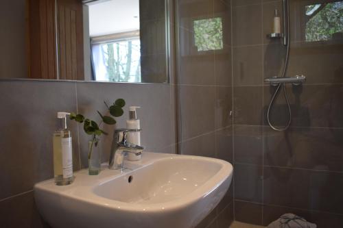 uma casa de banho com um lavatório branco e um chuveiro em The Steading em Aberfeldy