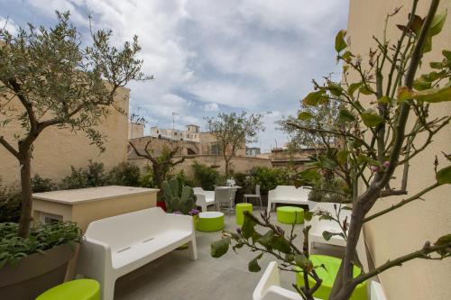 a patio with white tables and chairs and trees at B&B MARSALA in Marsala