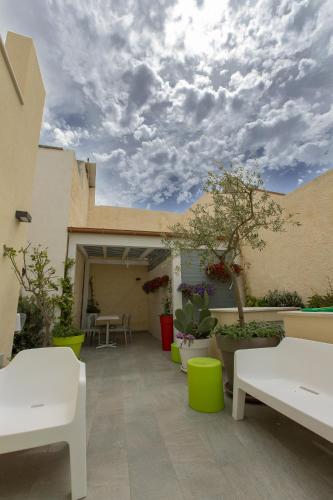 a patio with white benches and potted plants at B&B MARSALA in Marsala