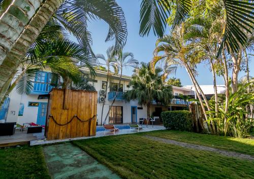 a house with a wooden gate and palm trees at Hotel IBIZA Beach Boutique in Jacó