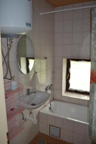 a bathroom with a sink and a tub and a mirror at Guest house Griva Plitvice in Korenica