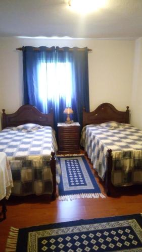 a bedroom with two beds and a window with blue curtains at Casa Reis in Santana