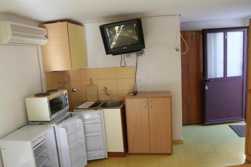 a kitchen with a microwave and a tv on the wall at Apartments Popović in Petrovac na Moru