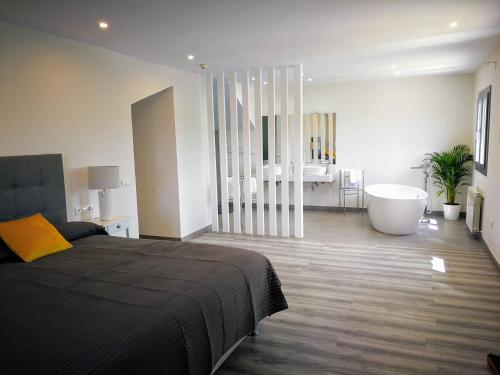 a bedroom with a bed and a tub and a bathroom at Hotel Ronda Moments in Ronda