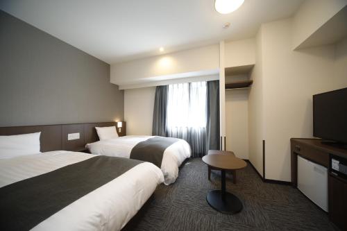 大分市にある天然温泉白糸の湯ドーミーイン大分のベッド2台、薄型テレビが備わるホテルルームです。