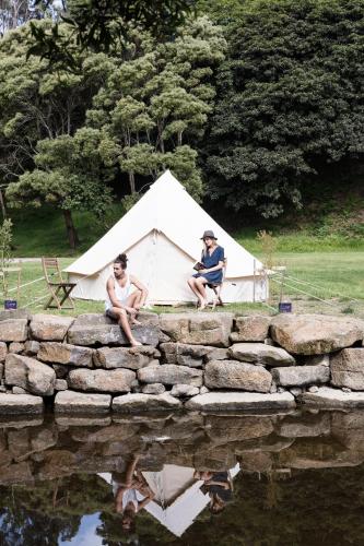 two men sitting on a stone wall with a white tent at BIG4 Wye River Holiday Park in Wye River