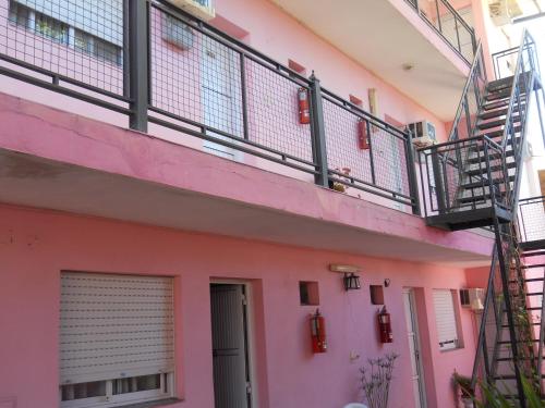 a pink building with a staircase on the side at Dennisse Hotel in Victoria