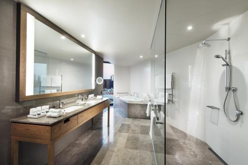 a bathroom with a tub, sink, and mirror at Pan Pacific Melbourne in Melbourne