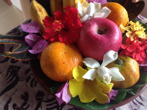 a bowl of flowers and an apple and oranges at Nirarta Center For Living Awareness in Sidemen