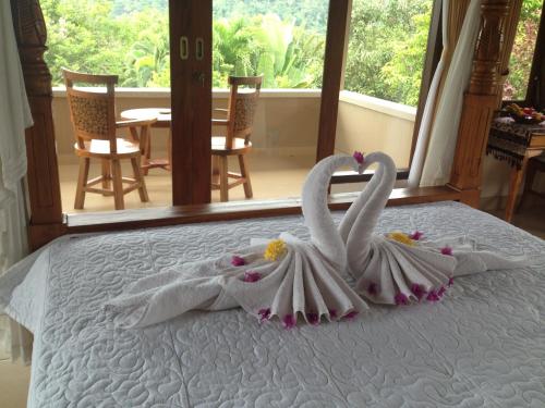 two swans dressed in white are sitting on a bed at Nirarta Center For Living Awareness in Sidemen