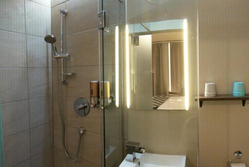 a bathroom with a shower with a sink and a mirror at Hotel Le Deville in Montreal