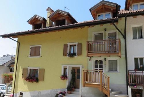 a yellow house with wooden balconies on top of it at Appartamento Lavarone in Lavarone