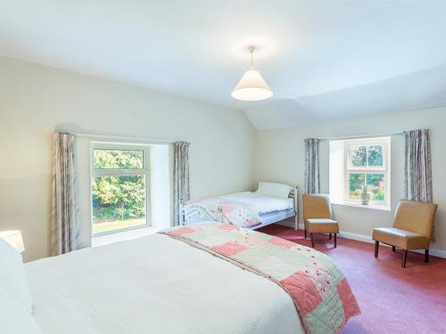 1 dormitorio con 2 camas y 2 ventanas en Curradoon House, en Ballynamult