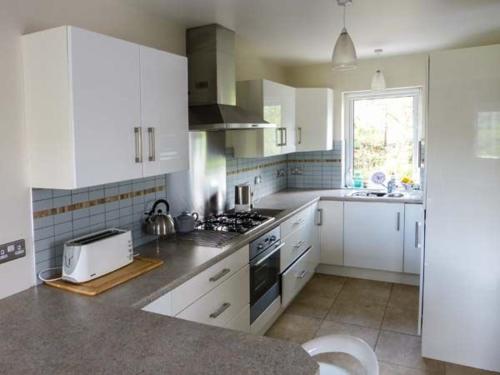 uma cozinha com armários brancos e um forno com placa de fogão em Loistin Coimin em Ballybofey