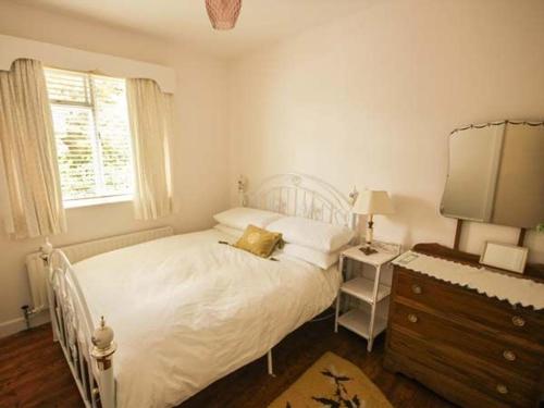 a bedroom with a white bed with a dresser and a window at Teach Annie in Falcarragh