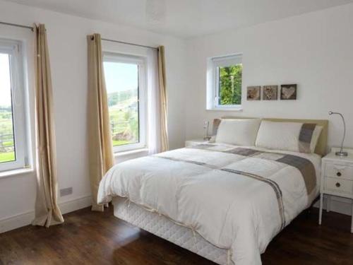 a white bedroom with a bed and two windows at Loistin Coimin in Ballybofey