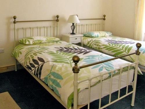 2 camas individuais num quarto com um candeeiro. em Kilkee Cottage em Kilkee