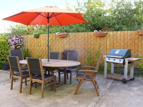 une table et des chaises avec un parasol et un grill dans l'établissement 19 River Glen, à Curracloe