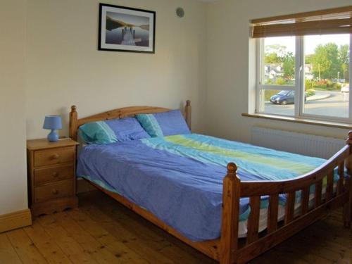 a bedroom with a wooden bed and a window at 19 River Glen in Curracloe