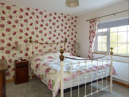 a bedroom with a bed with flowers on the wall at Brandy Harbour Cottage in Kilcolgan