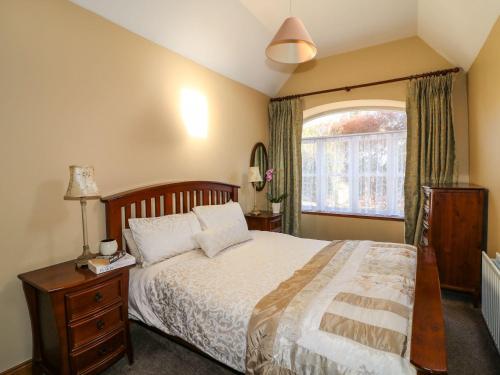 Un dormitorio con una cama grande y una ventana en Rosemount Coach House, en Ballycarney