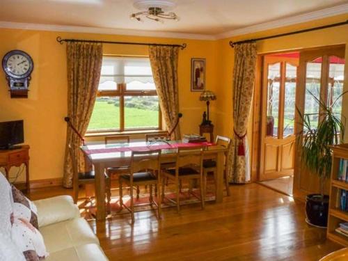 a living room with a table with chairs and a clock at Caola Nua in Kilcrohane