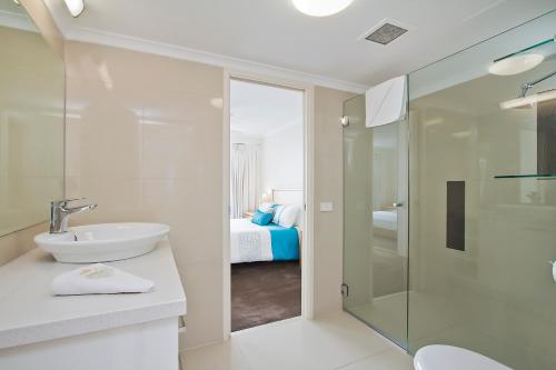 a white bathroom with a sink and a shower at South Pacific Plaza - Official in Gold Coast