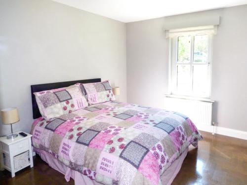 1 dormitorio con 1 cama con edredón rosa y gris en Hidden Gem Cottage, en Dungloe