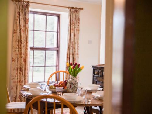 a dining room table with a vase of flowers on it at Shepherds' Retreat in Greencastle