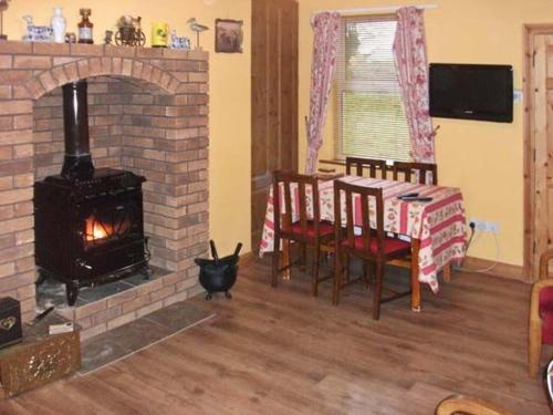 a living room with a fireplace and a table with chairs and a fire place at Hazel Cottage in Kilmore