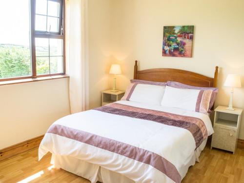 1 dormitorio con 1 cama grande y 2 ventanas en Flynn's Cottage, en Miltown Malbay