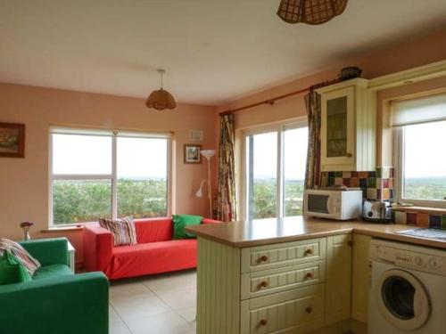 uma cozinha e sala de estar com um sofá vermelho em 5 Rinevilla View em Cross