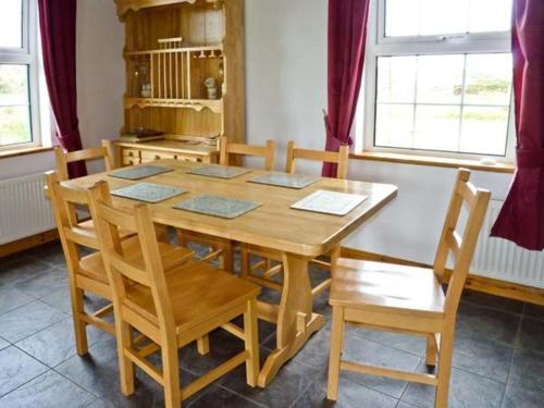 a wooden table and chairs in a room at Lully More Cottage in Doochary