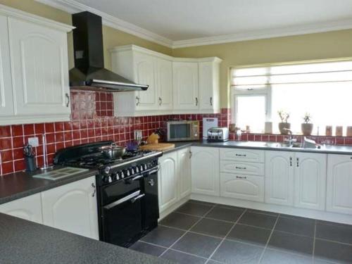 a kitchen with white cabinets and a black stove at Carraig Oisin in Waterville