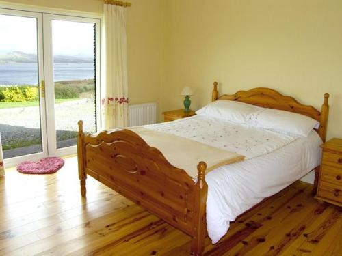 sypialnia z drewnianym łóżkiem i dużym oknem w obiekcie Lough Currane Cottage w mieście Waterville