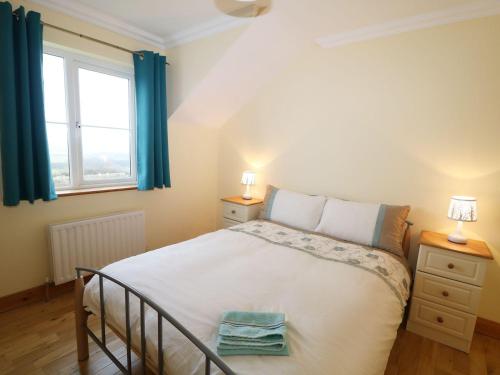 a bedroom with a bed and a window with blue curtains at Benbulben View in Tullaghan