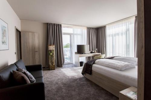 monte mare SAUNA-SPA-SPORTS-HOTEL في أندرناخ: غرفه فندقيه بسرير واريكه
