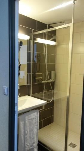 a bathroom with a shower and a sink at Hôtel de La Cloche in Dole