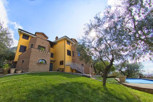una grande casa gialla con un albero di fronte di Villa C Luxury Estate a SantʼAntonio Abate
