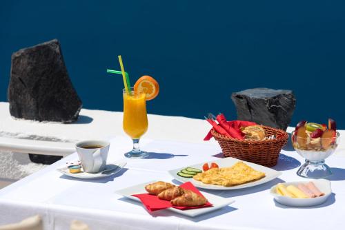 a table topped with plates of food and a drink at Iriana Suites in Fira