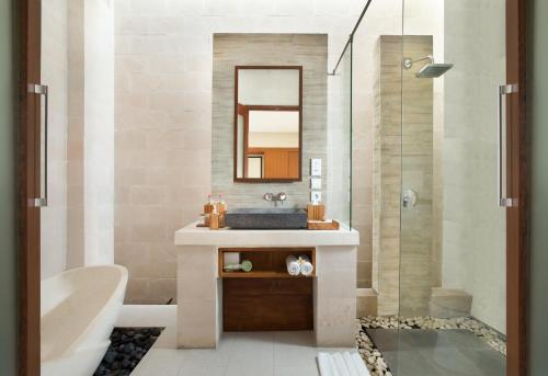 a bathroom with a sink and a shower with a mirror at Daluman Villas in Seminyak