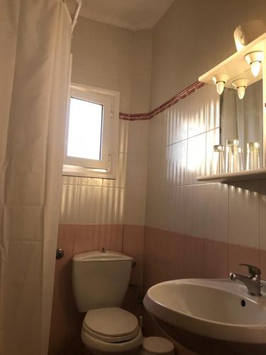 baño con aseo y lavabo y ventana en Agnanti, en Ávdhira