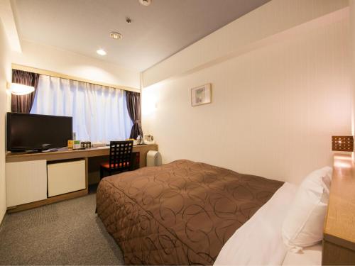 a hotel room with a bed and a desk at Osaka Moriguchi Plaza Hotel in Osaka