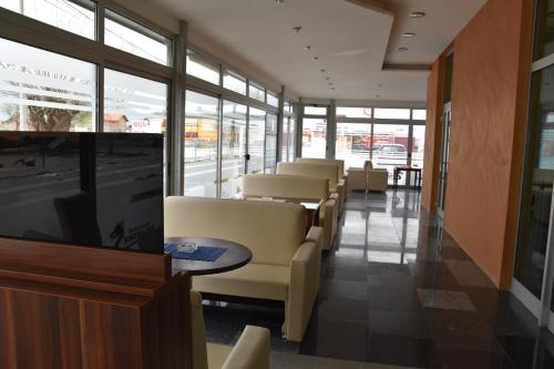 a waiting room with chairs and tables and windows at Hotel & Restaurant Great Wall - Airport in Sarajevo