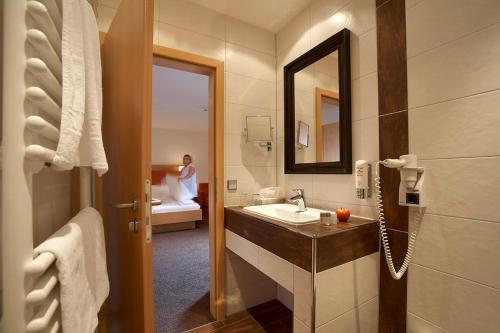 a bathroom with a sink and a person in a bed at Landgasthof zum Lamm in Bahlingen