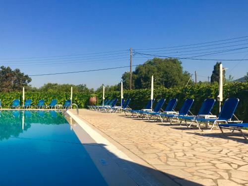 
a pool with chairs and umbrellas in it at IONIAN SUITES by Bruskos in Agios Georgios
