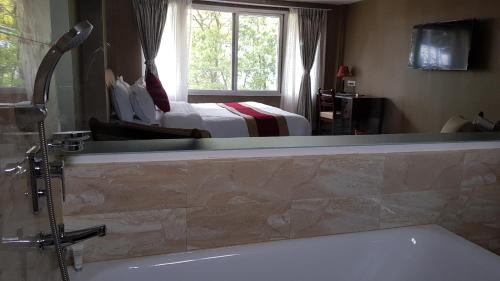 a bathroom with a bath tub and a bedroom at Himalayan Front Hotel by KGH Group in Pokhara