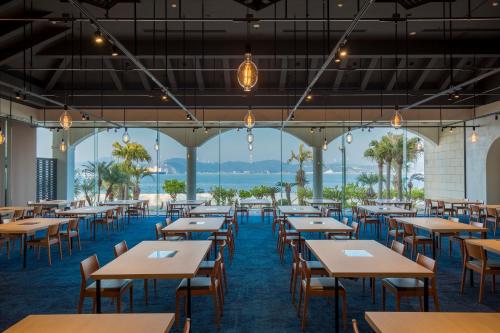 a restaurant with tables and chairs and a view of the ocean at i + Land Nagasaki in Nagasaki