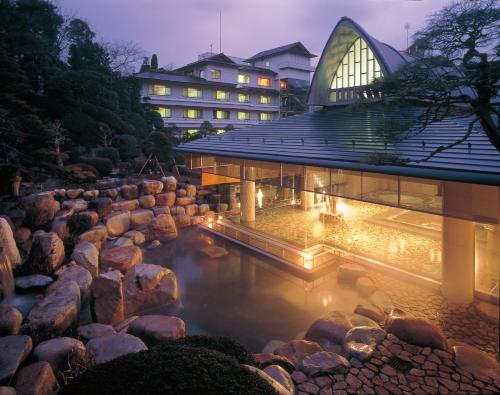 a building with a pool of water and rocks at Tamatsukuri Grand Hotel Choseikaku in Matsue